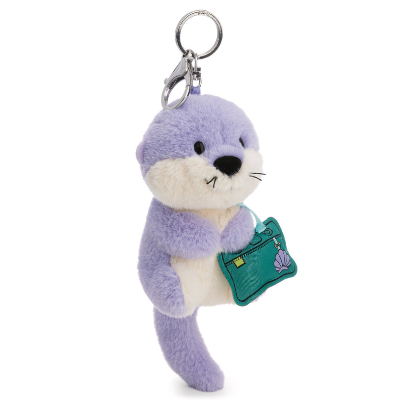Plüsch-Otter Ophelio lila mit einer grünen Handtasche mit Muschelmotiv und silberfarbenem Karabiner